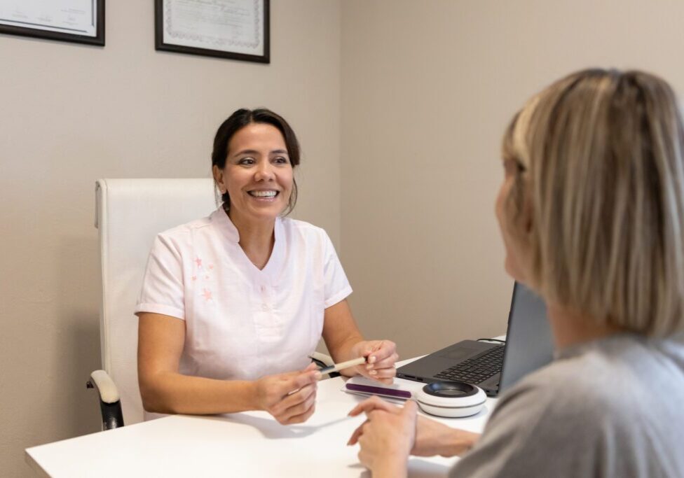 A healthcare professional smiling while consulting a patient.