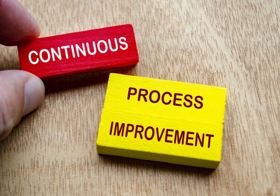 Blocks labeled 'Continuous' and 'Process Improvement' on a wooden surface.